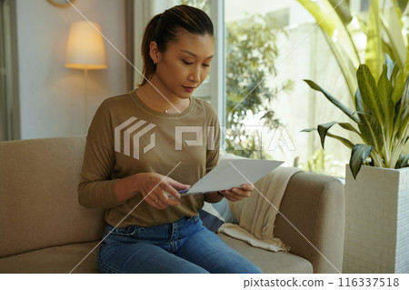 Woman Opening Bank Letter At Home Woman Opening Bank Letter At Home 116337518