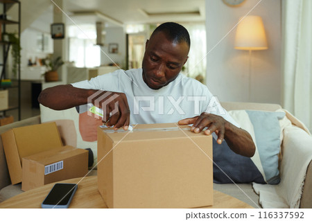 Man Unpacking His Boxes At Home 116337592