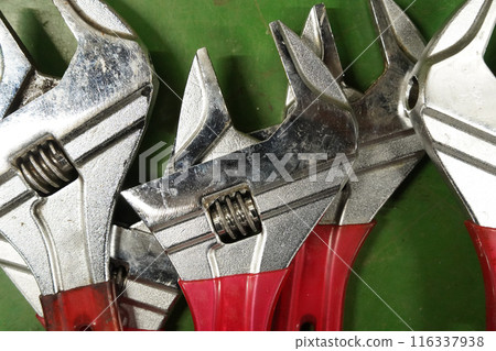 Adjustable wrench on the green background, closeup of photo Adjustable wrench on the green background, closeup of photo 116337938
