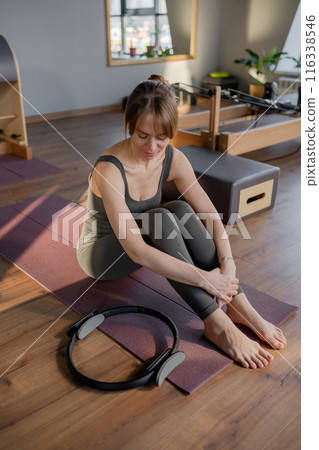 Calm and peaceful woman resting after training in pilates studio. A woman is engaging in a Pilates exercise session using Pilates equipment  116338546