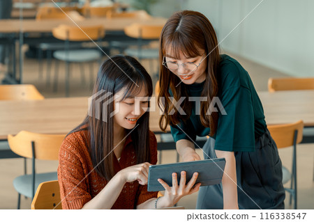 Two businesswomen having a meeting while looking at a tablet 116338547