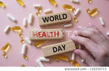 World Health Day symbol. Concept words World Health Day on wooden blocks. Beautiful pink background with pills. Doctor hand. Healthcare and World Health Day concept. Copy space. World Health Day symbol. Concept words World Health Day on wooden blocks. Beautiful pink background with pills. Doctor hand. Healthcare and World Health Day concept. Copy space. 116338713