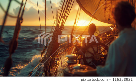 A man and a woman enjoy a serene sailing experience at sunset, with the golden light illuminating the sails and ocean waves 116338921