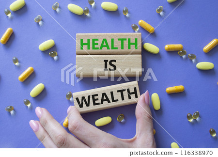 Health is Wealth symbol. Concept word Health is Wealth on wooden blocks. Doctor hand. Beautiful purple background with pills. Medicine and Health is Wealth concept. Copy space 116338970