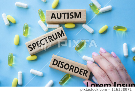 Autism Spectrum Disorder symbol. Concept word Autism Spectrum Disorder on wooden blocks. Doctor health. Beautiful blue background with pills. Medicine and Autism Spectrum Disorder concept. Copy space 116338971
