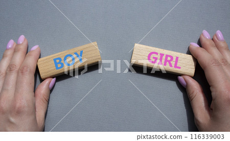Boy or Girl symbol. Concept word Boy or Girl on wooden blocks. Man hand. Beautiful grey background. Gender and Boy or Girl concept. Copy space 116339003