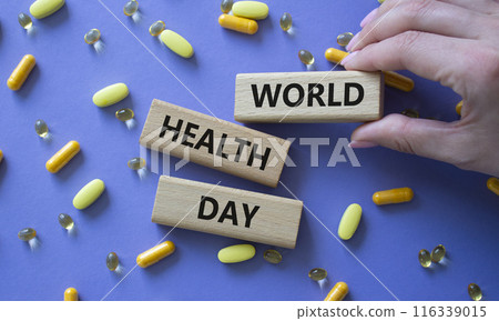 World Health Day symbol. Concept words World Health Day on wooden blocks. Beautiful purple background with pills. Doctor hand. Healthcare and World Health Day concept. Copy space. 116339015