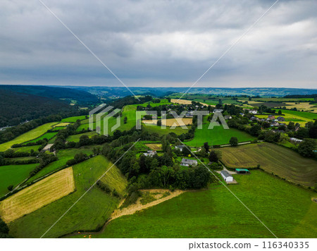 Aerial view captures lush countryside with rolling hills and farmland stretching into the distance 116340335