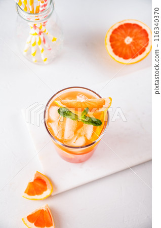 Fresh grapefruit juice with ice, mint and grapefruit slice in a glass on a white marble background Fresh grapefruit juice with ice, mint and grapefruit slice in a glass on a white marble background 116340370