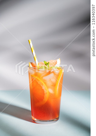 Fresh grapefruit juice with ice, mint and grapefruit slice in a glass on a blue background Fresh grapefruit juice with ice, mint and grapefruit slice in a glass on a blue background 116340397