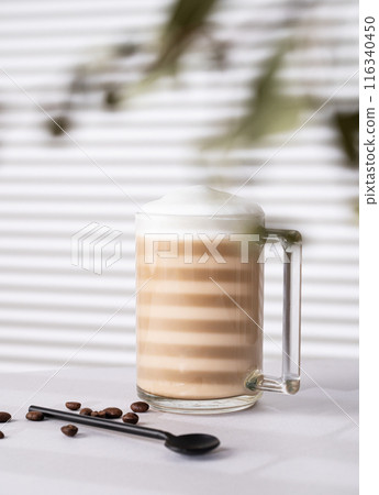 Cappuccino or latte with milk foam in a cup with coffee beans on light background Cappuccino or latte with milk foam in a cup with coffee beans on light background 116340450