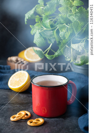 Red  cup of tea with lemon, mint and salt cracker on dark background. The concept of mood breakfast 116340451