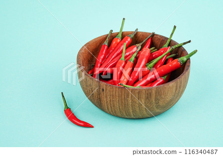 Red hot chili pepper in a wooden bowl on a blue background close-up. Copy space Red hot chili pepper in a wooden bowl on a blue background close-up. Copy space 116340487