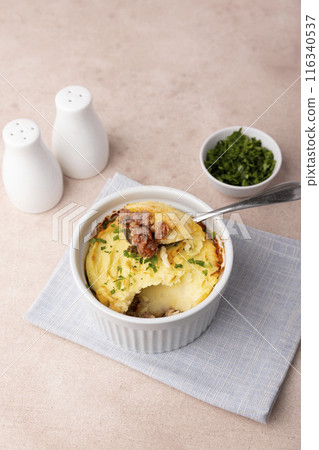 Shepherd's pie in a portioned white baking dish. Homemade traditional casserole (gratin) with minced meat and mashed potatoes. Selective focus, close-up. 116340537