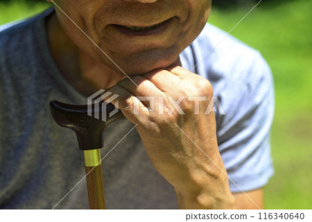 Smiling old man walking with a cane 116340640