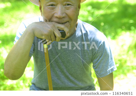 Smiling old man walking with a cane 116340651