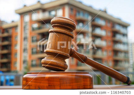 Wooden gavel with a residential apartment building in the background 116340703