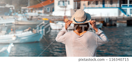 Girl in a hat travels, enjoys beautiful views on the seashore. 116340715