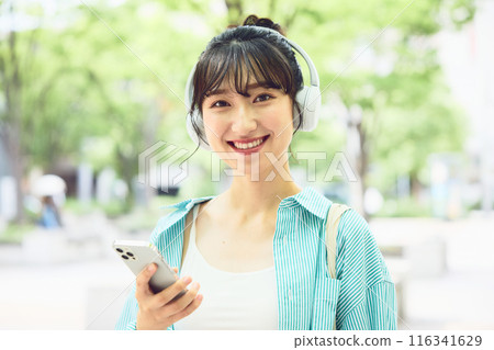 Female college student listening to music with headphones 116341629