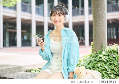 Female college student listening to music with headphones 116341634