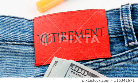 Conceptual RETIREMENT symbol. Copy space. RETIREMENT on the red leather label of jeans on a white background in a composition with American dollars 116341671