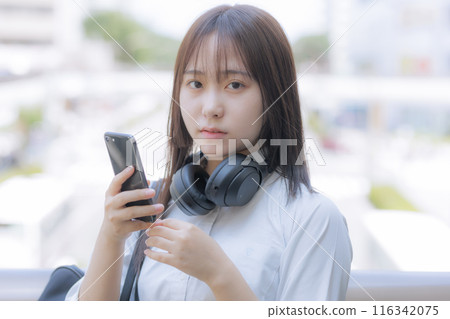 在城市裡聽音樂時使用智慧型手機的高中女孩 在城市裡聽音樂時使用智慧型手機的高中女孩 116342075