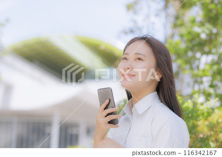 A high school girl sitting in the street and using a smartphone 116342167