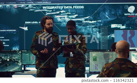 Officers team managing air traffic control for military aircrafts within the operational area, using CCTV radar surveillance. Evaluating and presenting mission plans to their crew. Camera A. 116342321