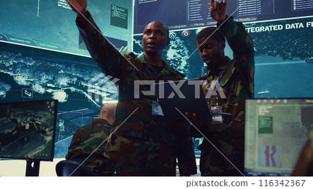 Army commanders overseeing field operations with real time data registered on surveillance CCTV systems. Military officials examining mission details, army defense program in power base. Camera B. Army commanders overseeing field operations with real time data registered on surveillance CCTV systems. Military officials examining mission details, army defense program in power base. Camera B. 116342367