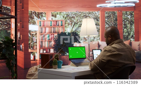 Businessman reviewing statistics reports next to an isolated mockup screen at home office, adviser calculating budget in order to expand the enterprise activity. Finance and economy. Camera B. Businessman reviewing statistics reports next to an isolated mockup screen at home office, adviser calculating budget in order to expand the enterprise activity. Finance and economy. Camera B. 116342389