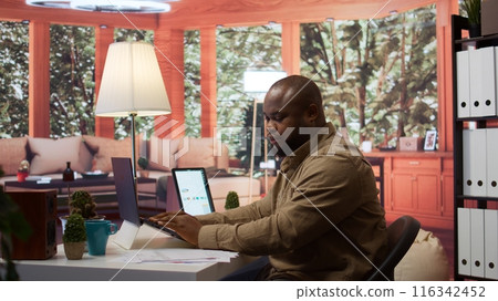 Startup administrator establishing current enterprise goals with annual data reports, exploring global partnership opportunities for the firm. Businessman doing win or loss study at home. Camera B. Startup administrator establishing current enterprise goals with annual data reports, exploring global partnership opportunities for the firm. Businessman doing win or loss study at home. Camera B. 116342452