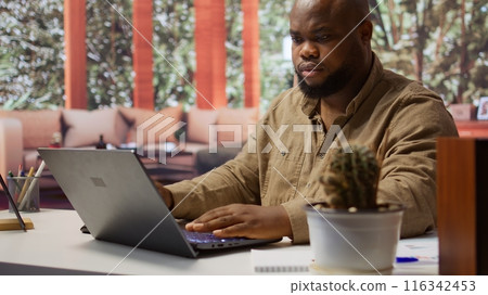 Self employed analyst working on financial audits and budget planning on his laptop, managing online marketing and development strategies for his personal trading business at home. Camera B. Self employed analyst working on financial audits and budget planning on his laptop, managing online marketing and development strategies for his personal trading business at home. Camera B. 116342453
