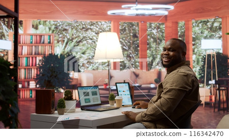 General manager examines financial reports and performance metrics to assess expansion plans from his home office. Business consultant reviews online infographics, balance and expenses. Camera B. 116342470