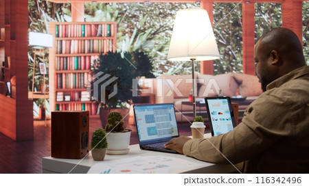 Startup entrepreneur looking into project details on laptop at his home setup, reviewing budget numbers and solving business tasks to achieve enterprise growth objectives. Camera B. Startup entrepreneur looking into project details on laptop at his home setup, reviewing budget numbers and solving business tasks to achieve enterprise growth objectives. Camera B. 116342496