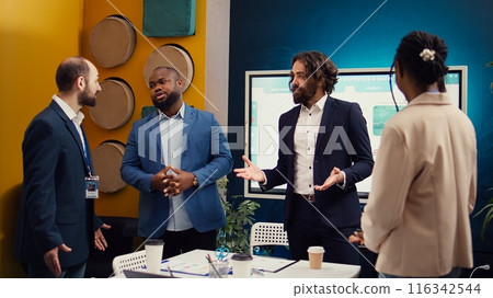 Coworkers from global business enterprise sharing ideas for products or services, debating a new marketing strategy during a briefing meeting. Employees collaborating on development. Camera B. 116342544