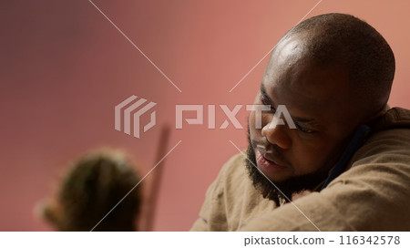 Business owner having a chat on phone call with the shareholders, communicating the current enterprise profit situation from his home office. Entrepreneur asking for new funding. Camera A. 116342578