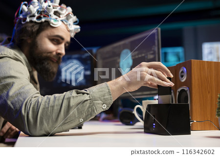 Engineer with EEG headset inserting cartridge into PC to use high tech software allowing for brain transfer into virtual world. Man putting disk in computer to start consciousness upload Engineer with EEG headset inserting cartridge into PC to use high tech software allowing for brain transfer into virtual world. Man putting disk in computer to start consciousness upload 116342602