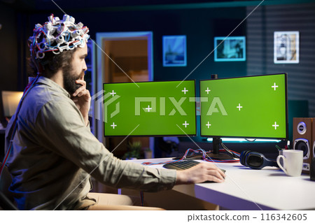 Man with EEG headset programs brain transfer into multimonitor setup green screen computer, merging with artificial intelligence. IT expert uses neuroscience and mockup desktop PC to gain digital soul Man with EEG headset programs brain transfer into multimonitor setup green screen computer, merging with artificial intelligence. IT expert uses neuroscience and mockup desktop PC to gain digital soul 116342605