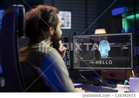 IT professional pleasantly surprised after managing to have conversation with artificial intelligence on computer. Programmer smiling looking at PC screen after achieving goal of talking with AI 116342653