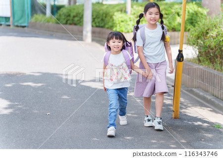 Elementary school students carrying backpacks to and from school 116343746