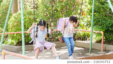 Elementary school students stop by the park after school to play on the swings 116343751
