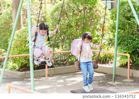 Elementary school students stop by the park after school to play on the swings Elementary school students stop by the park after school to play on the swings 116343752