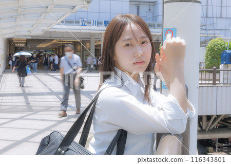 A high school girl holding a bag while meeting someone in the city 116343801