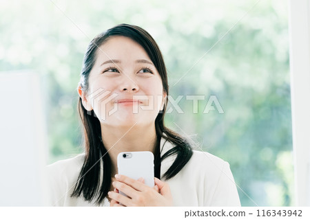 Young woman holding smartphone at work Young woman holding smartphone at work 116343942