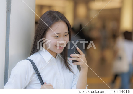 A high school girl talking on the phone in the city 116344016