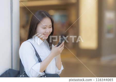 High school girl using a smartphone in the city 116344065