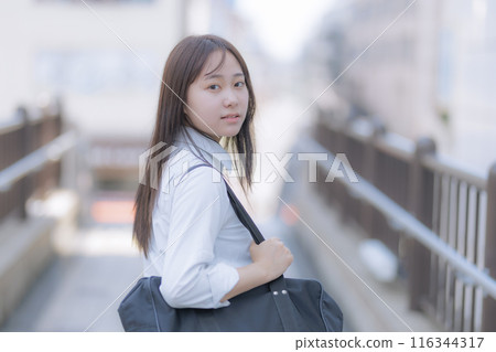 背著書包在城裡行走的高中女孩 背著書包在城裡行走的高中女孩 116344317