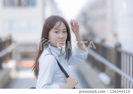 A high school girl walking around town with a bag 116344319