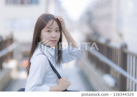 A high school girl walking around town with a bag 116344320