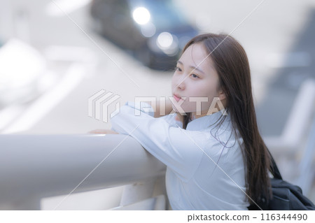 一個高中女生背著包包站在街上 116344490